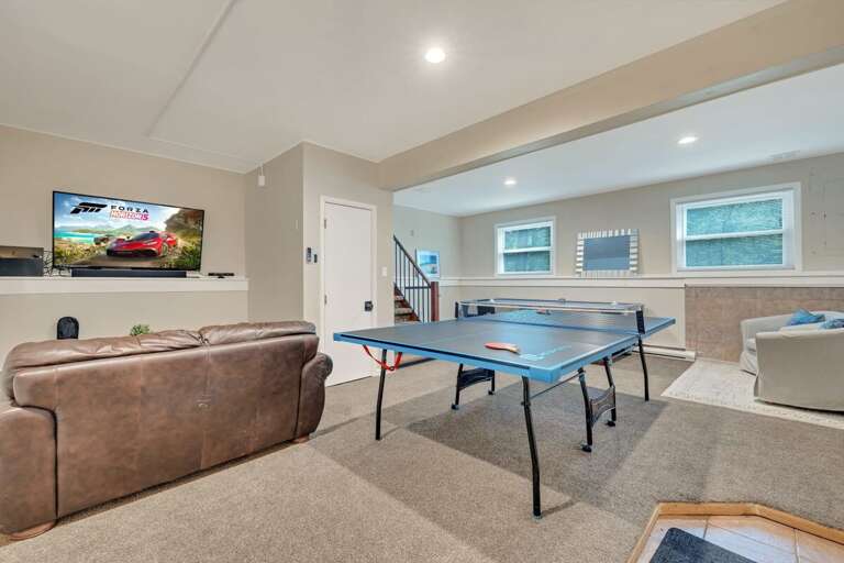 Basement Playroom With Ping Pong Table, Large TV, And Brown Sofa